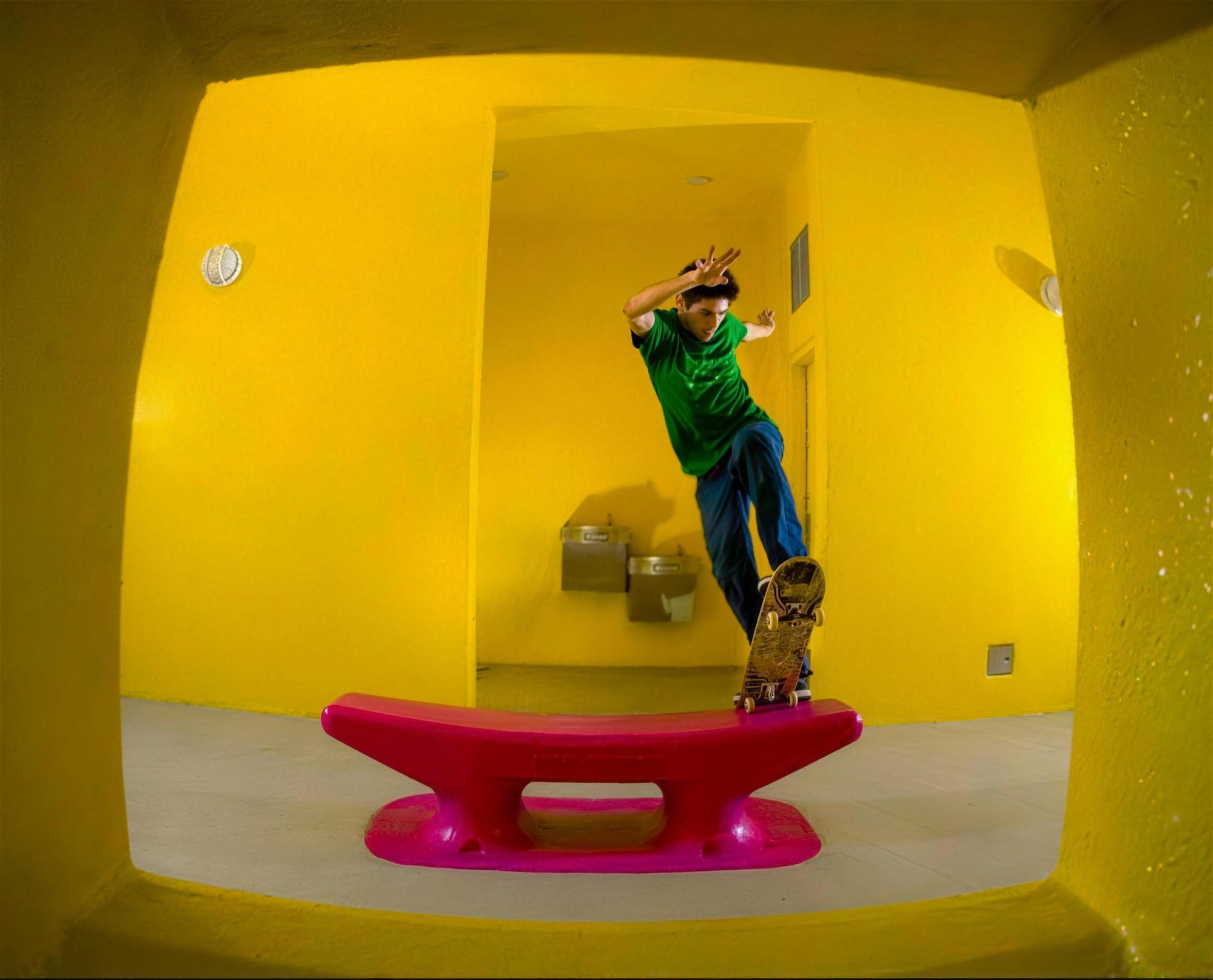 Skater haciendo un truco en un pasillo amarillo, foto con lente ojo de pez