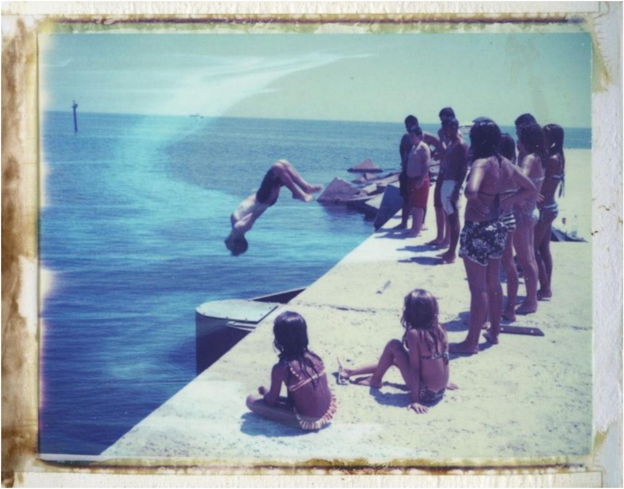 Polaroid de niños saltando y observando desde un muelle junto al mar